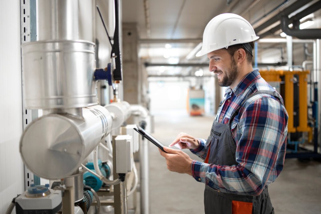 engineer worker holding tablet computer and setting parameters of heating system in factory boiler room.